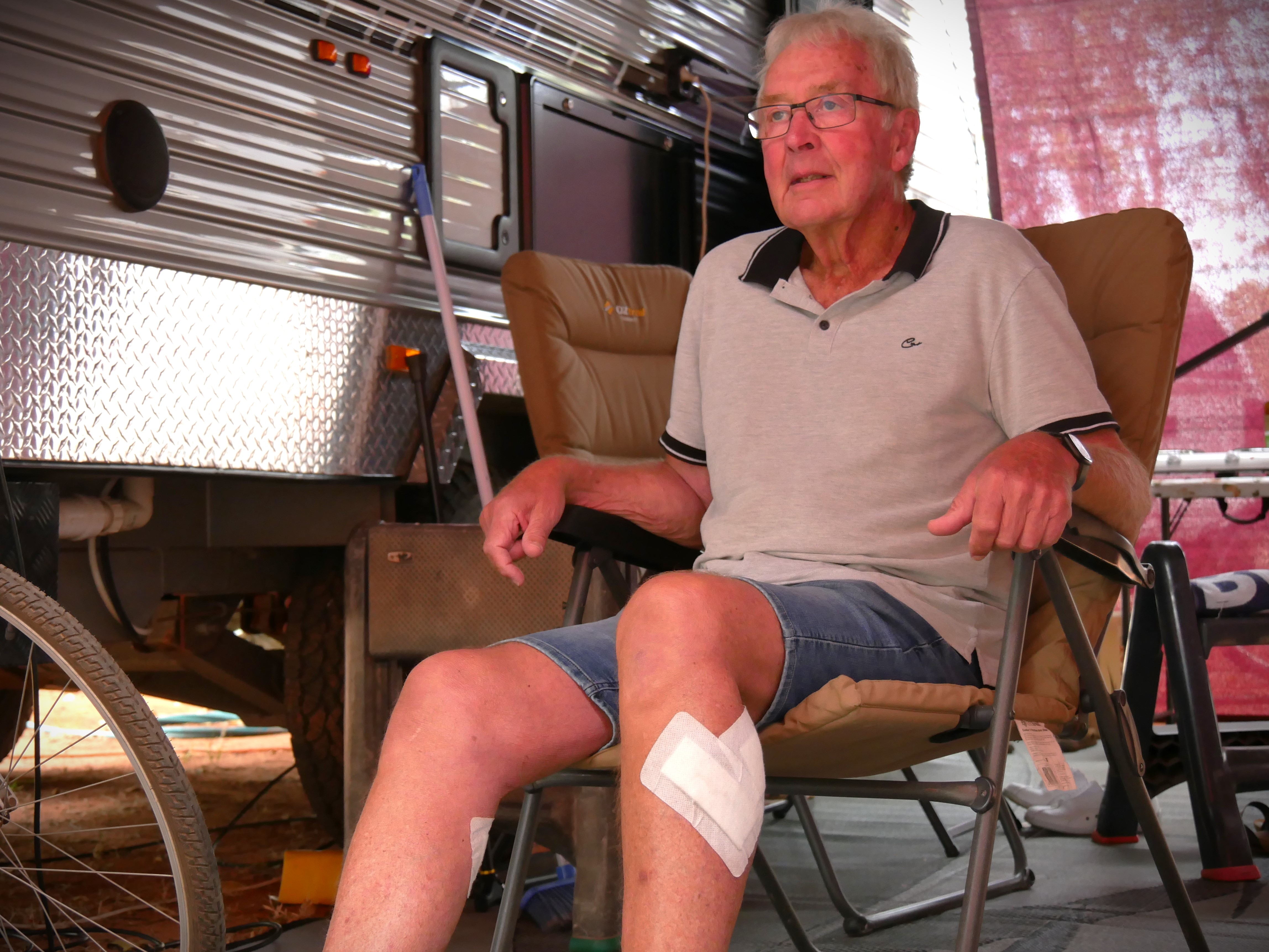 An elderly man sitting on a deck chair with a bandage on his leg