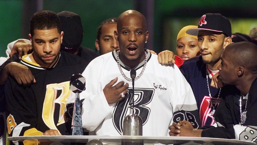A group of hip hop artists behind a podium at an awards show.