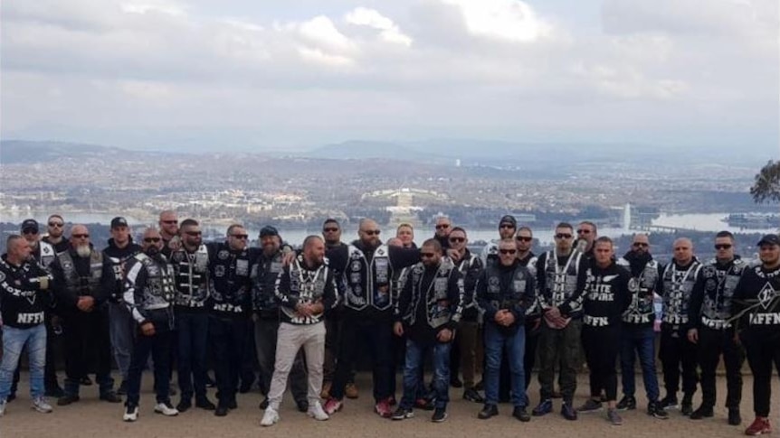 A group of bikies stand on Mount Ainslie with Canberra in background