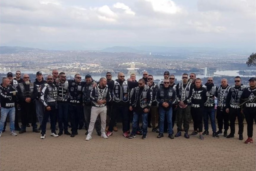 A group of bikies stand on Mount Ainslie with Canberra in background
