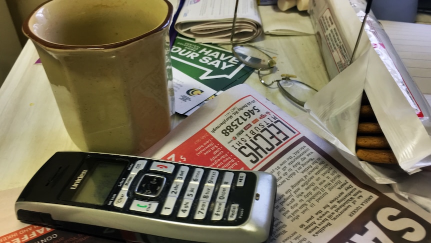 Cordless phone on messy kitchen table