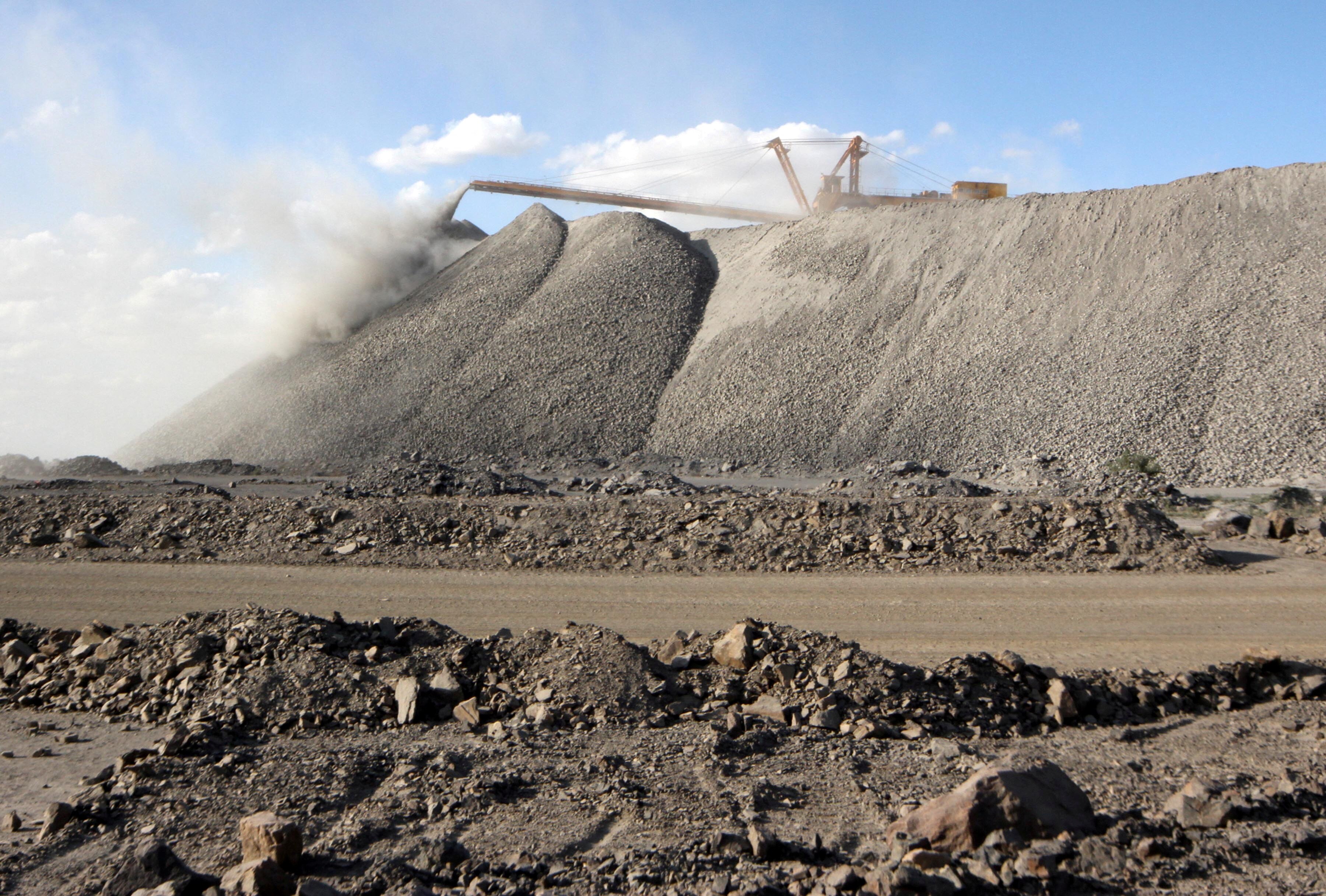 A large pile of a black mineral. Rocky ground is in the foreground.