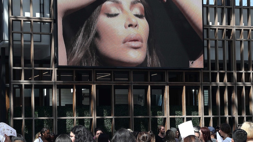 People walk past a billboard ad featuring Kim Kardashian