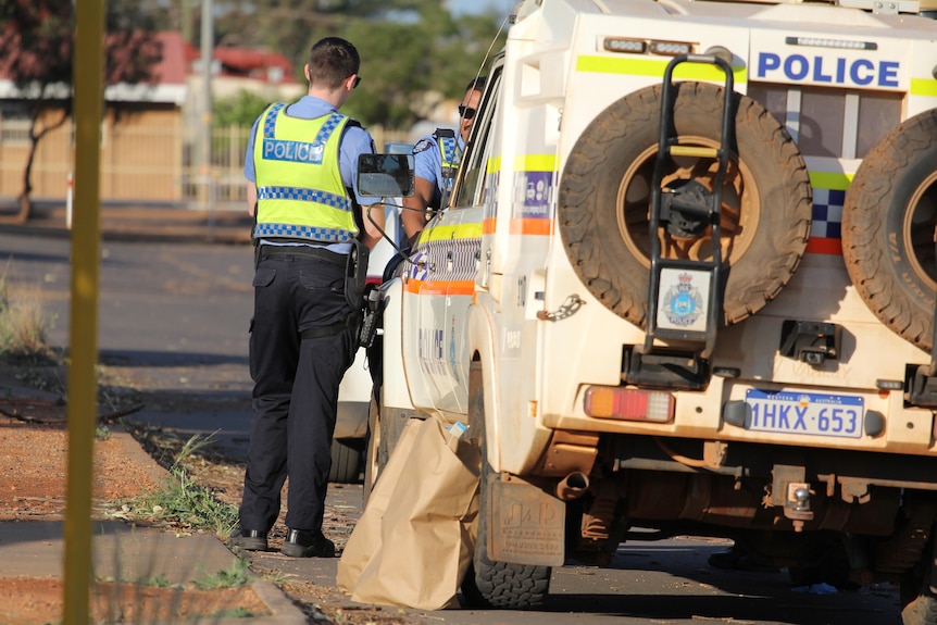 Two uniformed police officers standing near a police vehicle in kalgoorlie