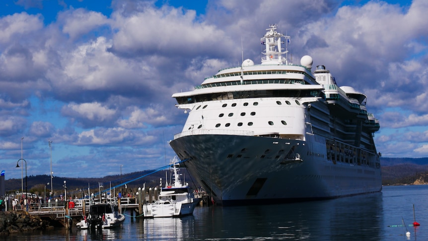 a huge cruise ship in the water with blue skies in the background