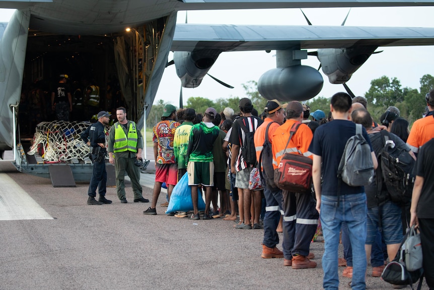 Royal Australian Air Force aviators assist Borroloola remote community members board a C-130J Hercules aircraft at the airport.