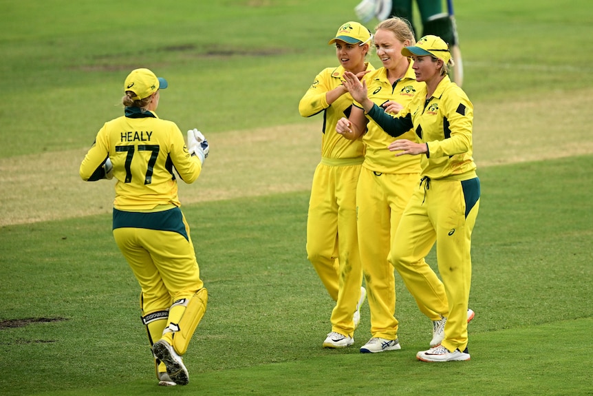 Australian women's cricket captain Alyssa Healy (left) runs to teammate Kim Garth (middle right) after taking a catch in an ODI.