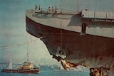 Colour photo of men on the bow of the HMAS Melbourne with its bow section damaged, with torn metal under the men