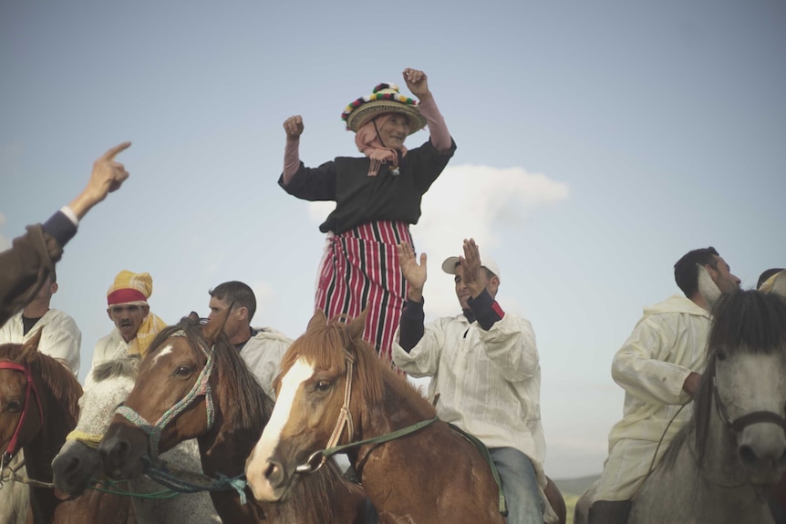 Zohra celebrates in colourful hat with male riders