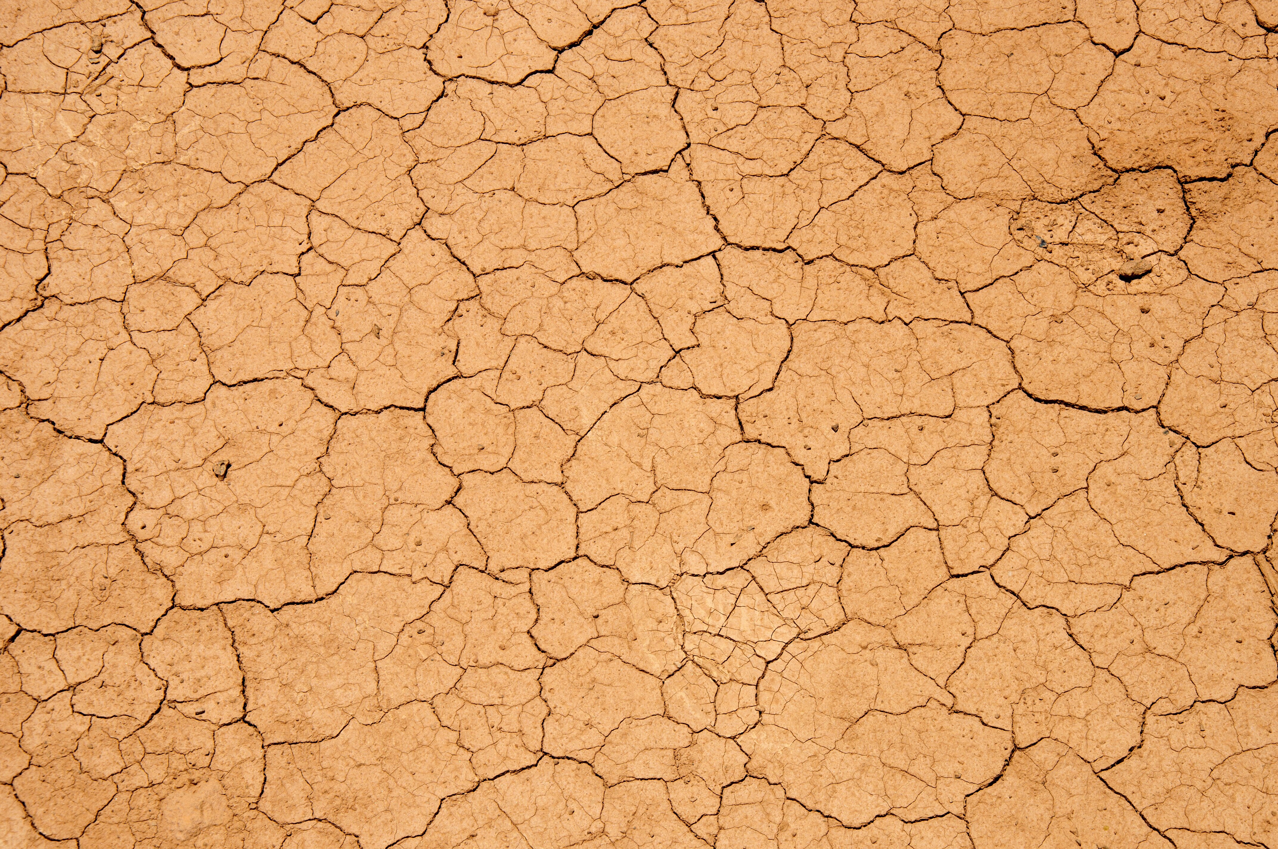 Dry, cracked red earth with the text "Drought"