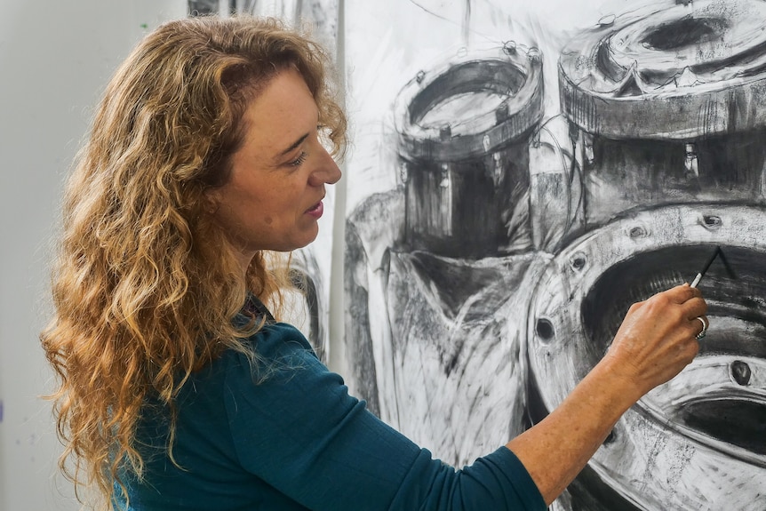 A woman using charcoal to draw. 
