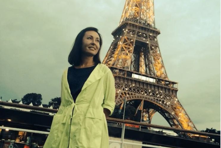 A woman poses in front of the Eiffel Tower 