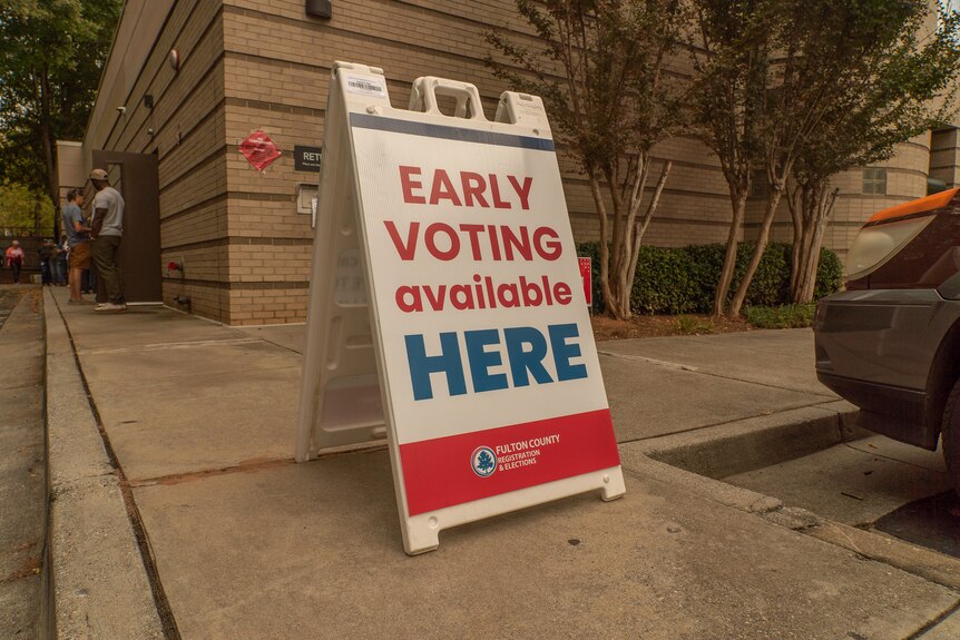 An A-frame sign reads "early voting here"