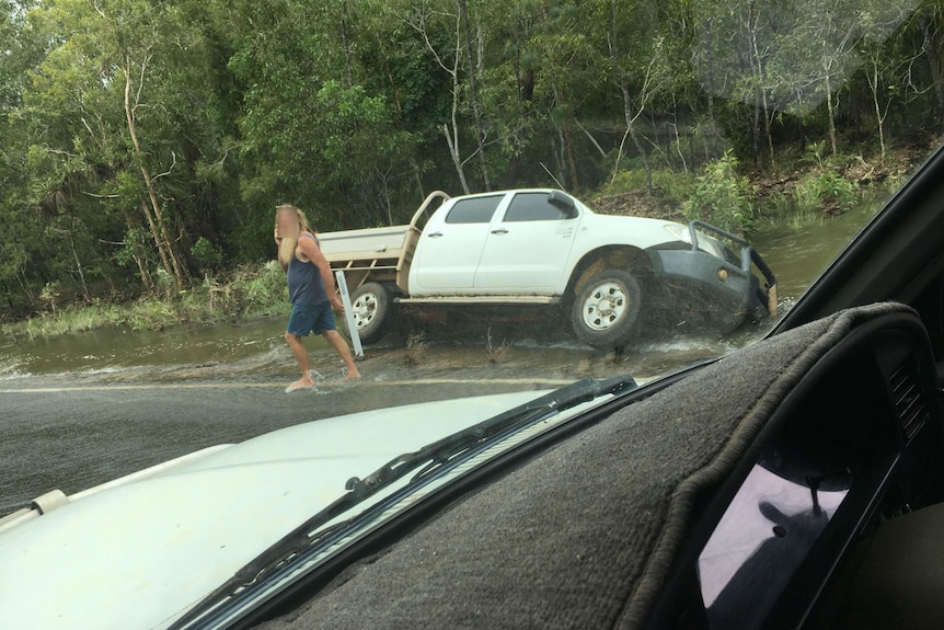 A dual-cab ute on it's side off a road.