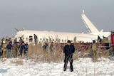In morning light, you see the crashed fuselage of a plane lying flat on the tarmac in snow.