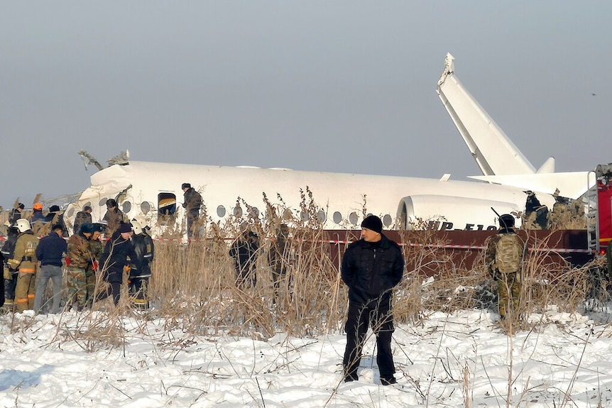 In morning light, you see the crashed fuselage of a plane lying flat on the tarmac in snow.