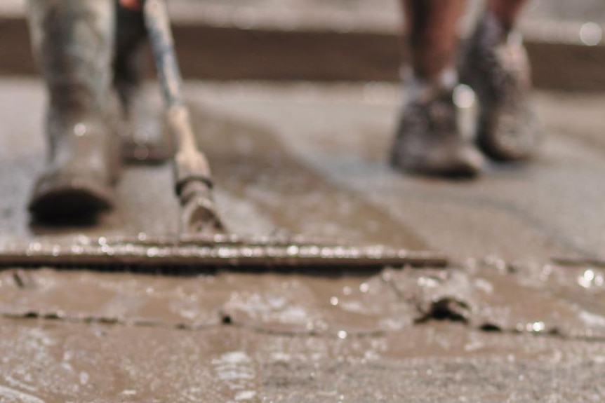 Close-up of volunteers wearing gumboots pushing river mud away with a squeegee after Brisbane flooded, January 15, 2011.