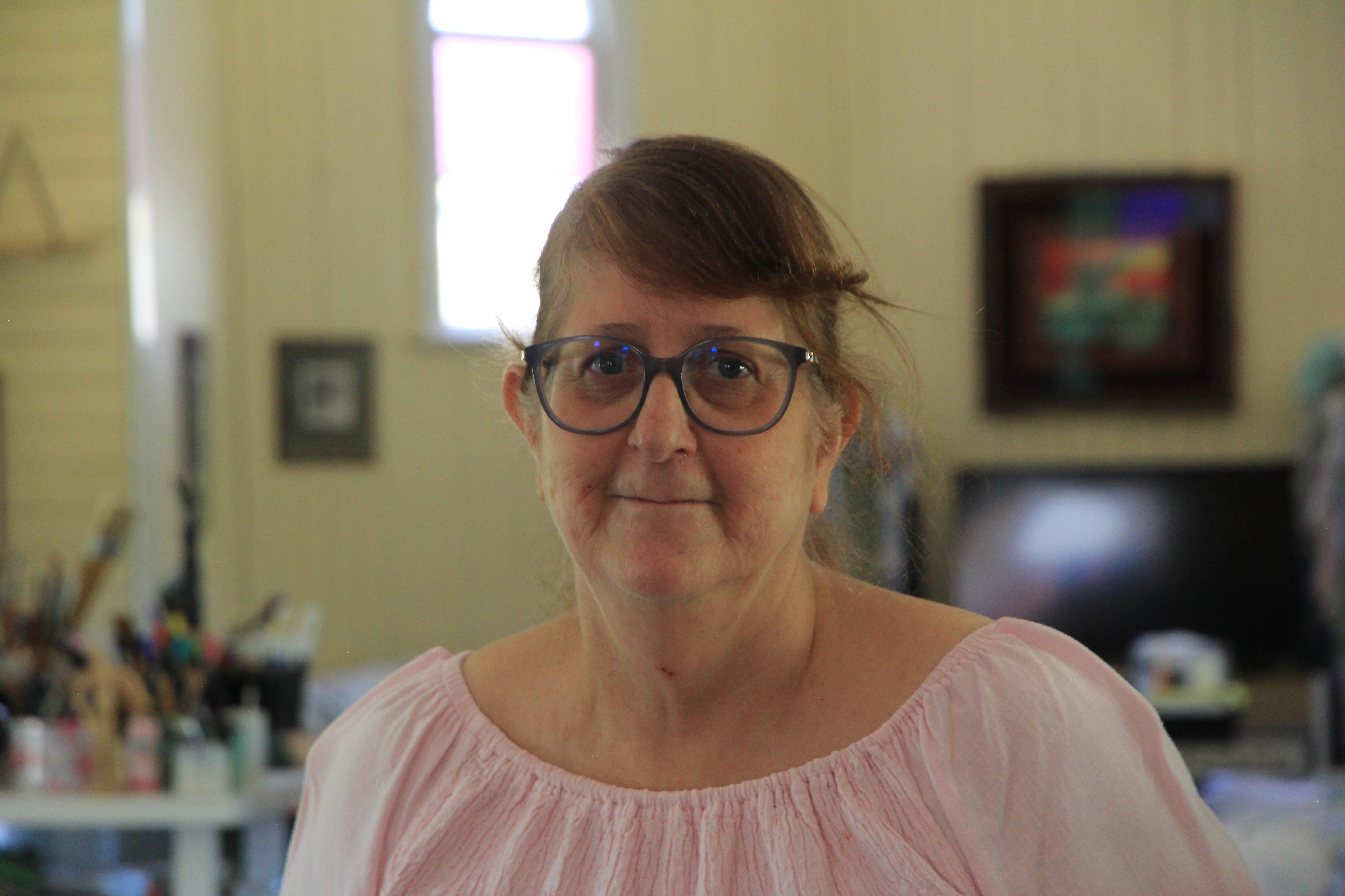 Женщина в очках стоит внутри своей церкви. 