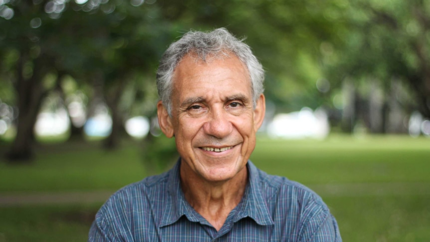 A man smiles in a park.