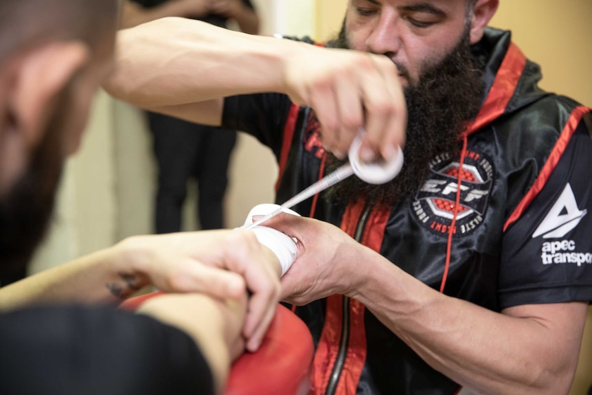 A man straps another man's hand for mixed martial arts.