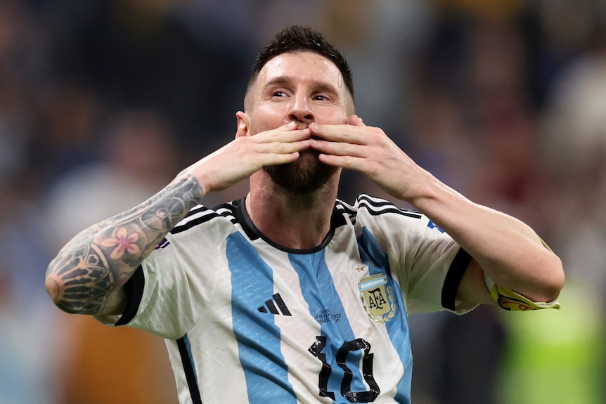 Lionel Messi holds both hands to his face as if to blow a kiss