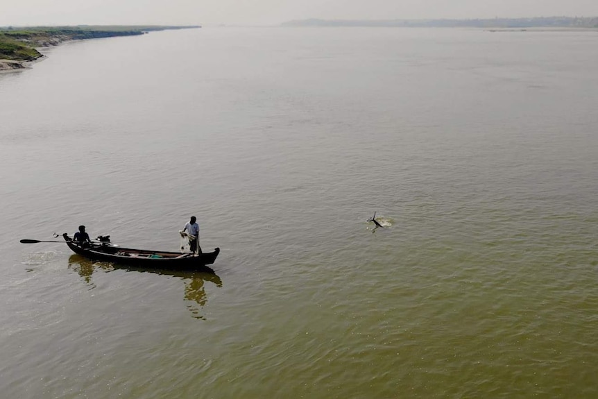 A dolphin waves its tail at some fisherman.