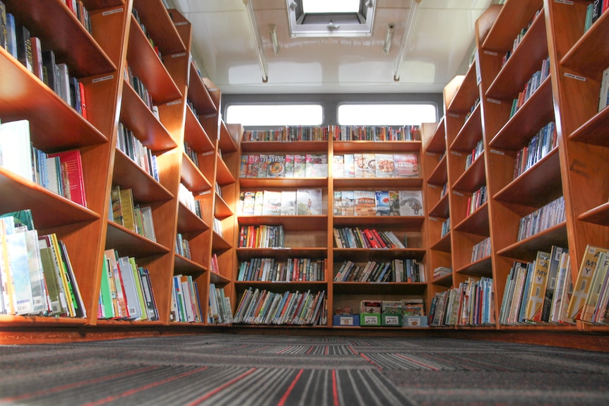The interior of the bookmobile is lined with wooden shelves covered in books
