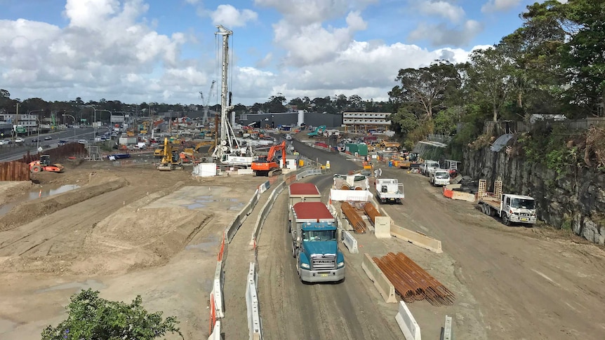 A large construction site with trucks, cranes and earth-moving vehicles.