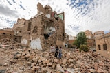 Three boys walk among the rubble of a bombed building in Sana'a, Yemen