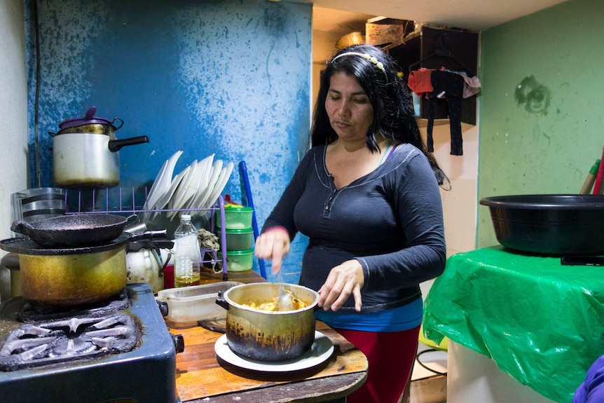 A woman cooks in a small, basic kitchen