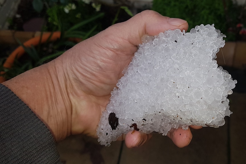 A hand holds a giant ball of hail