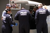 Forensic police stand around a wall