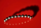 A bright red background shows a chain of small magnet balls in a curve formation.