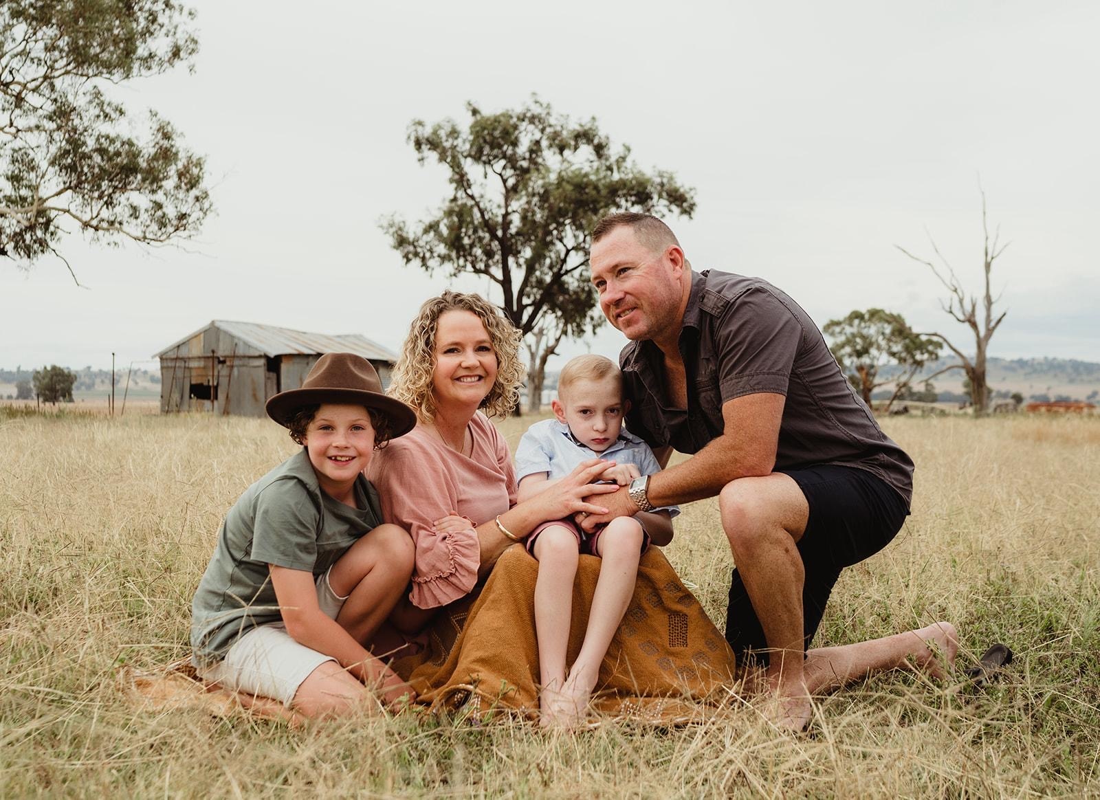 The Lawson family sitting in a paddock, smiling at the camera 