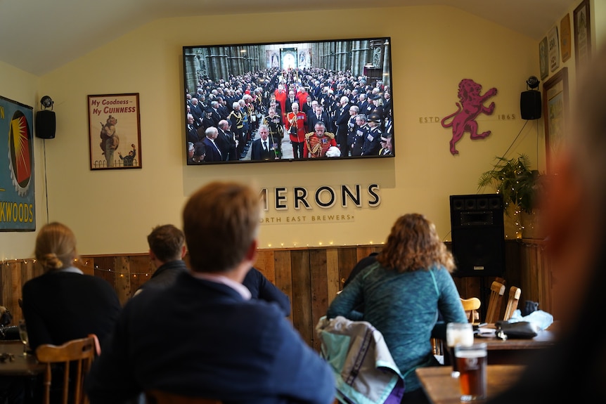 People watch the procession in a pub. 