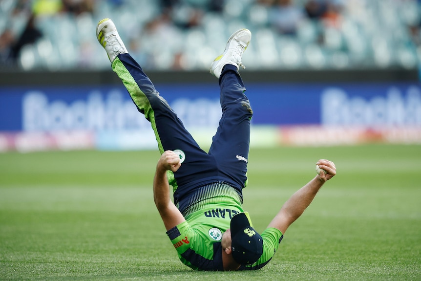 Daniel Pockett rolls onto his back and has his legs in the air as he holds onto the ball after taking a catch