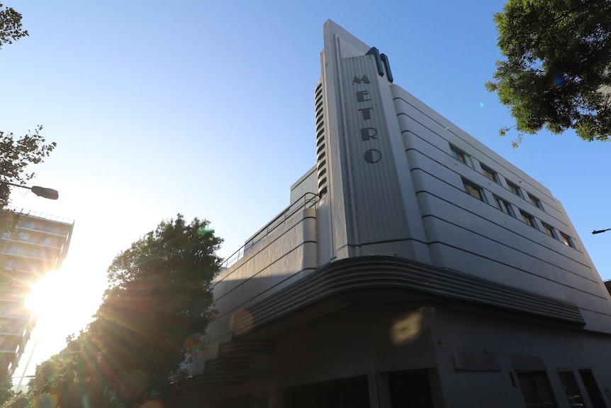 A white and blue art deco theatre with the word 'Metro' on it, as the sun sets
