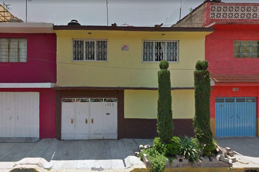 A two-storey yellow painted house in a street.