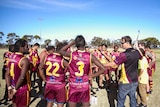 A group of players stand around while assistant coach Brenton Meynell goes through the game plan.