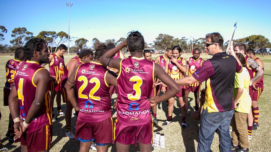 A group of players stand around while assistant coach Brenton Meynell goes through the game plan.