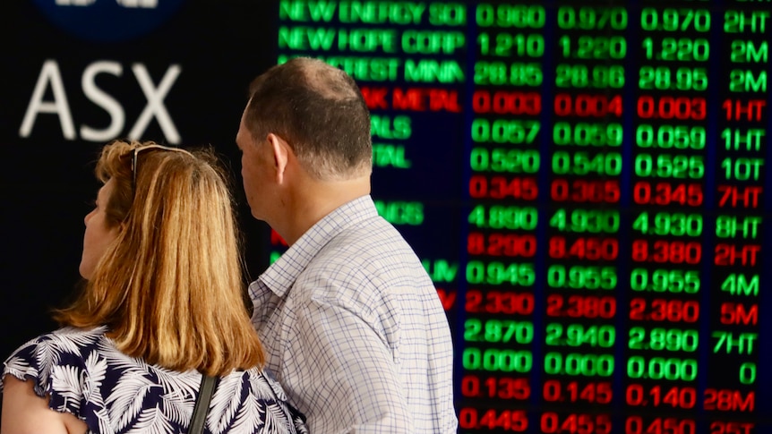 A woman and a man look at the Australian Security Exchange boards in Sydney