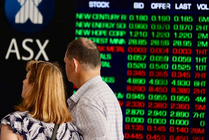 A woman and a man look at the Australian Security Exchange boards in Sydney