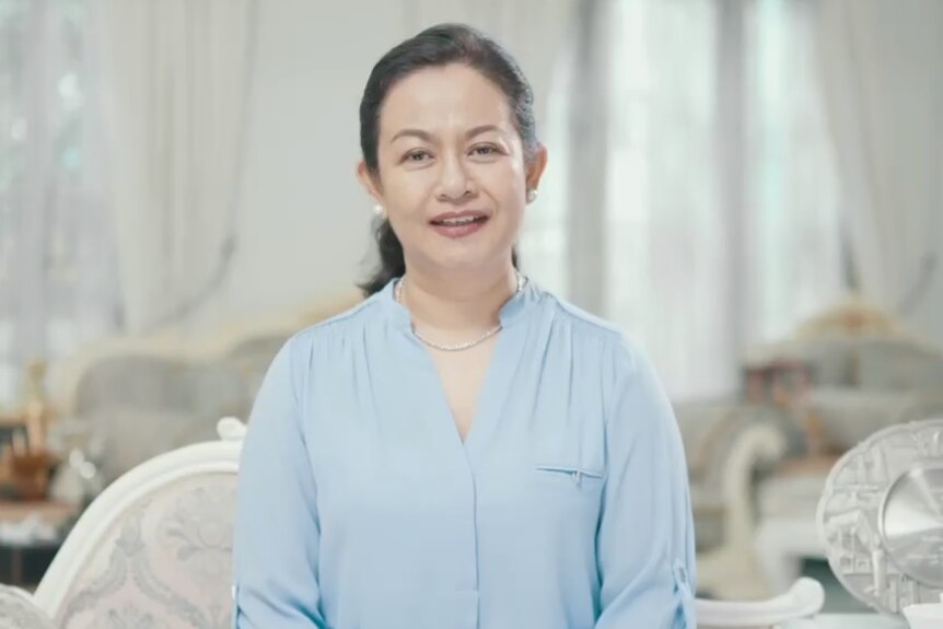 Thet Thet Khine in a pale blue shirt wearing pearls with nice furniture in the background.
