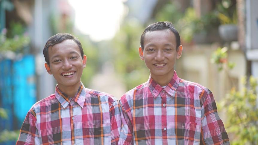 Riky and Riko Prawoto in Indonesia's 'twin village'. They are identical twins and are wearing matching red plaid shirts.