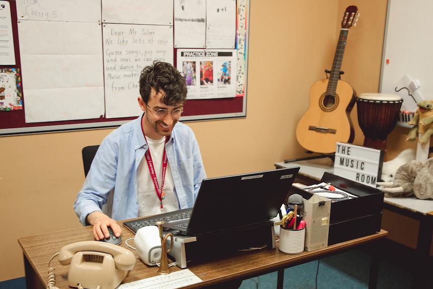 A man sitting at a desk in front of a laptop