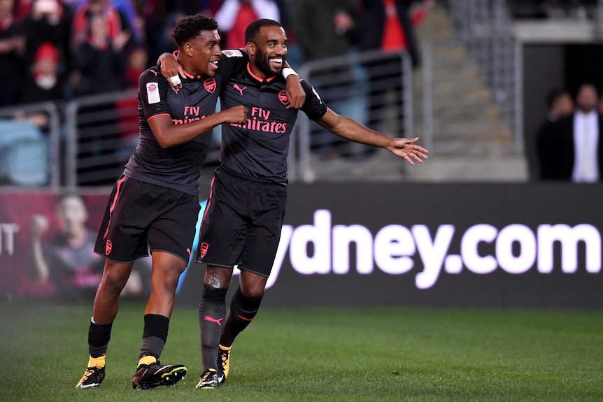 Alexandre Lacazaette and Alex Iwobi embrace with smiles on their faces as they celebrate an Arsenal goal against Sydney FC.