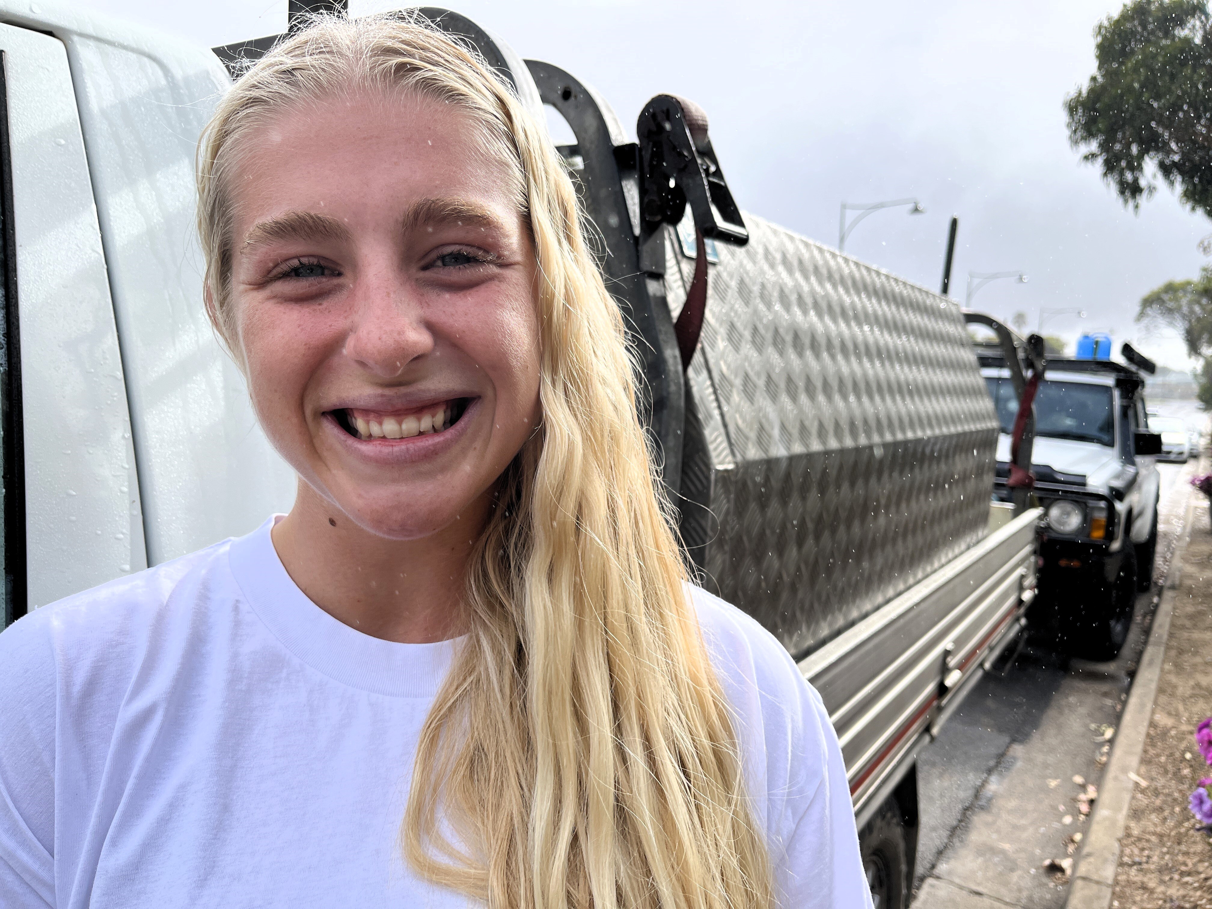 A young woman stands next to a ute