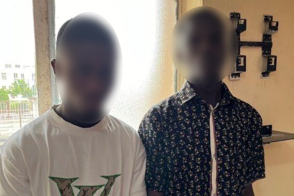 A photo of two men standing in a room with their faces blurred.
