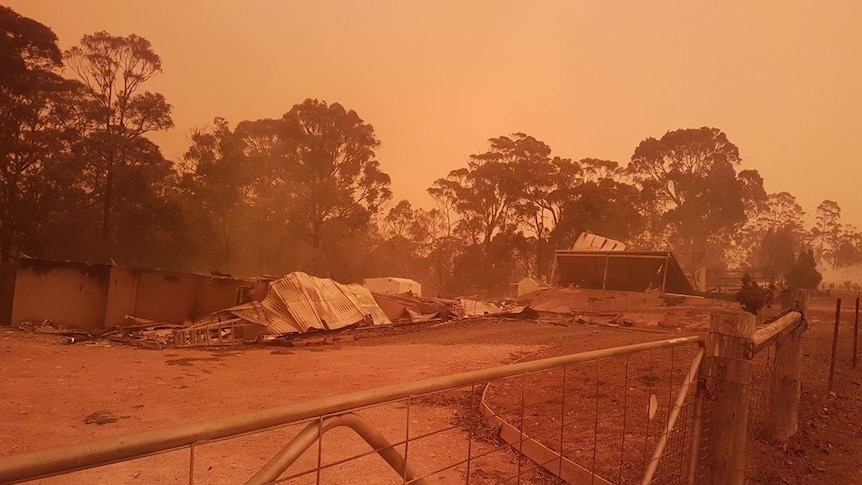 A razed home against and orange sky.