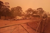 A razed home against and orange sky.